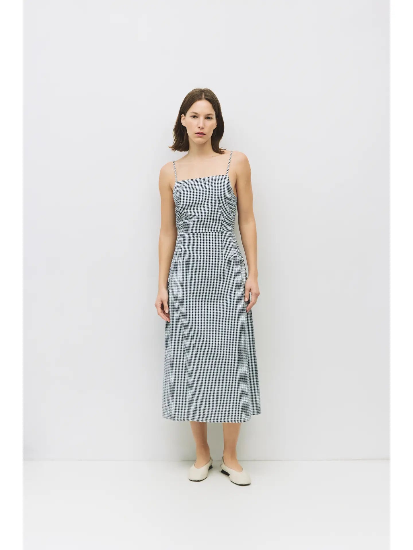 The Campbell Dress is a sleeveless, gingham seersucker dress with a square neckline and adjustable straps. Featuring a double tie-back detail and elastic back waistline, it's both comfortable and flattering for warm days.