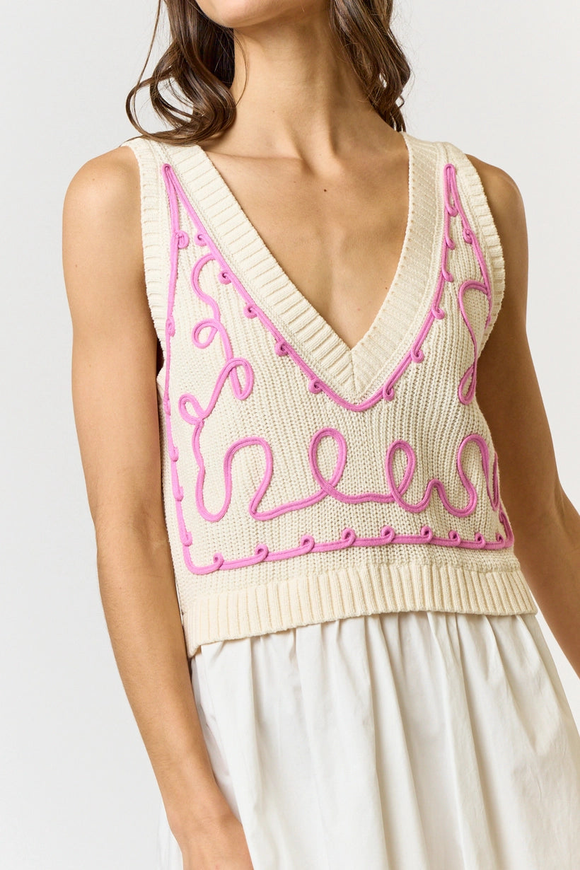 Deep v neck sweater vest dress with embroidered detailing.