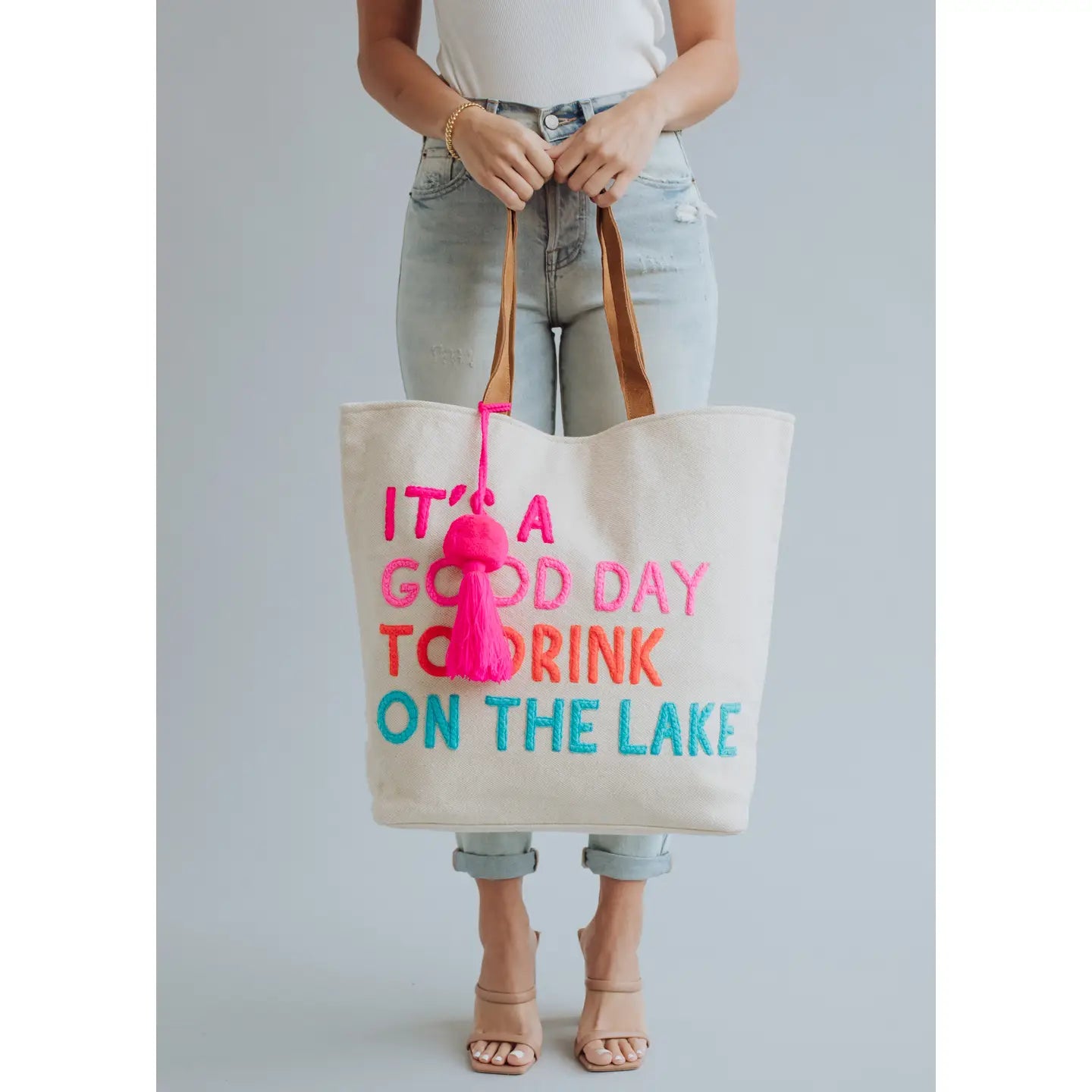 Extra large canvas cream tote with colorful embroidered words "It's a good day to drink on the lake" included with magnetic zipper, double shoulder handle and interior pockets.