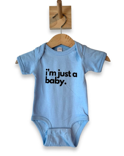 Baby onesie in light blue with black bold letters "i'm just a baby" perfect for a new baby gift.