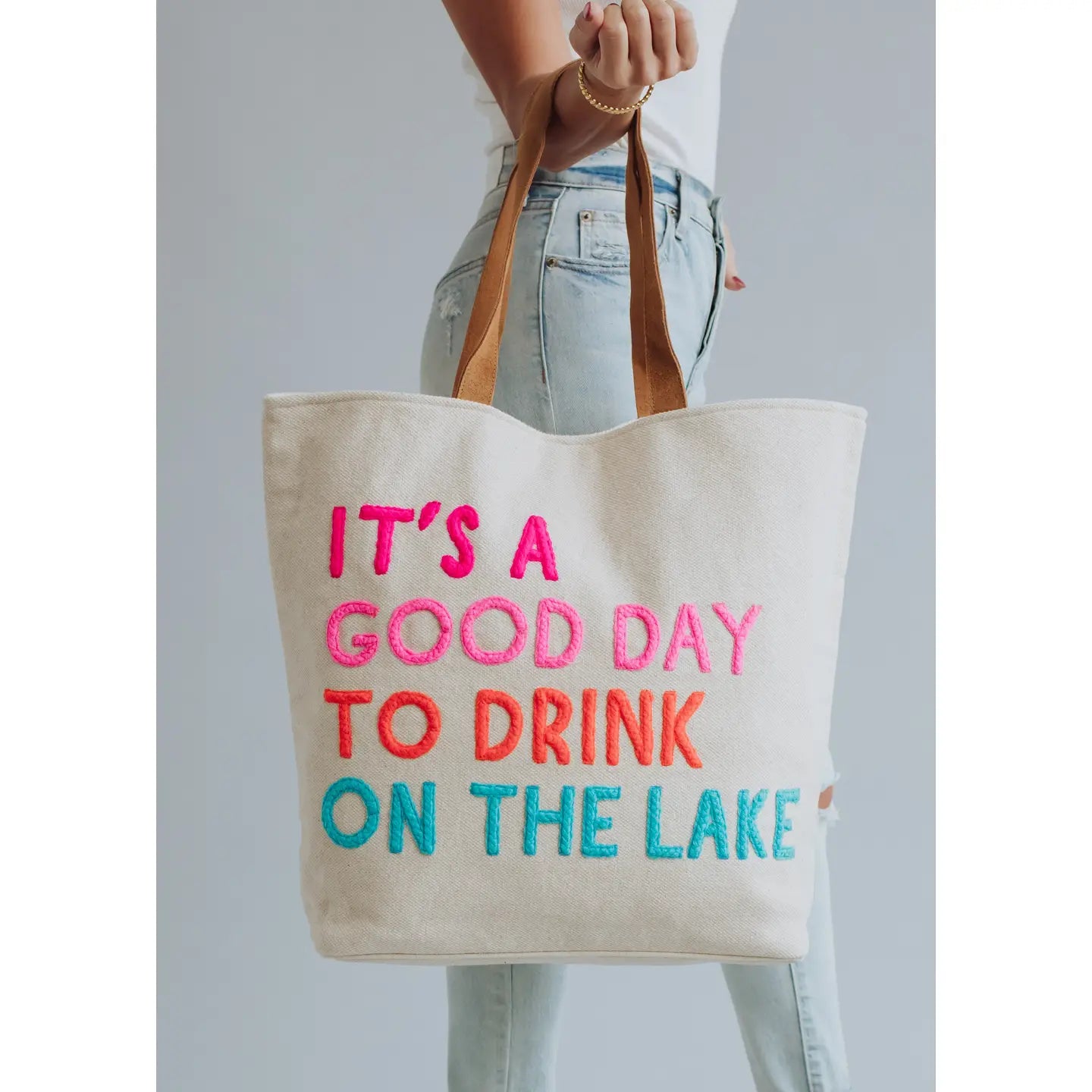 Extra large cream tote with colorful embroidered words "It's a good day to drink on the lake" included with magnetic zipper, double shoulder handle and interior pockets.