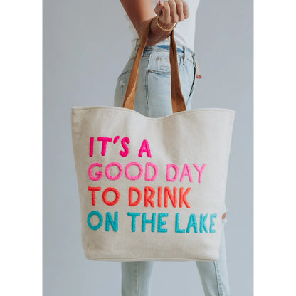 Extra large cream tote with colorful embroidered words "It's a good day to drink on the lake" included with magnetic zipper, double shoulder handle and interior pockets.