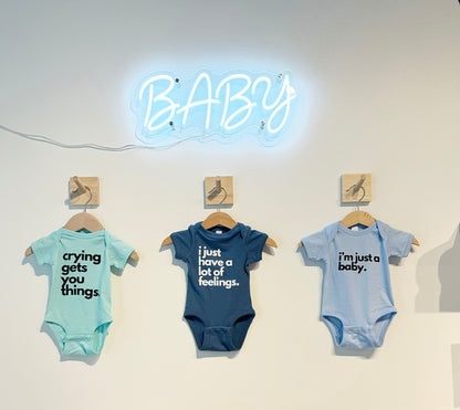 Baby onesie in light blue with black bold letters "i'm just a baby" perfect for a new baby gift.