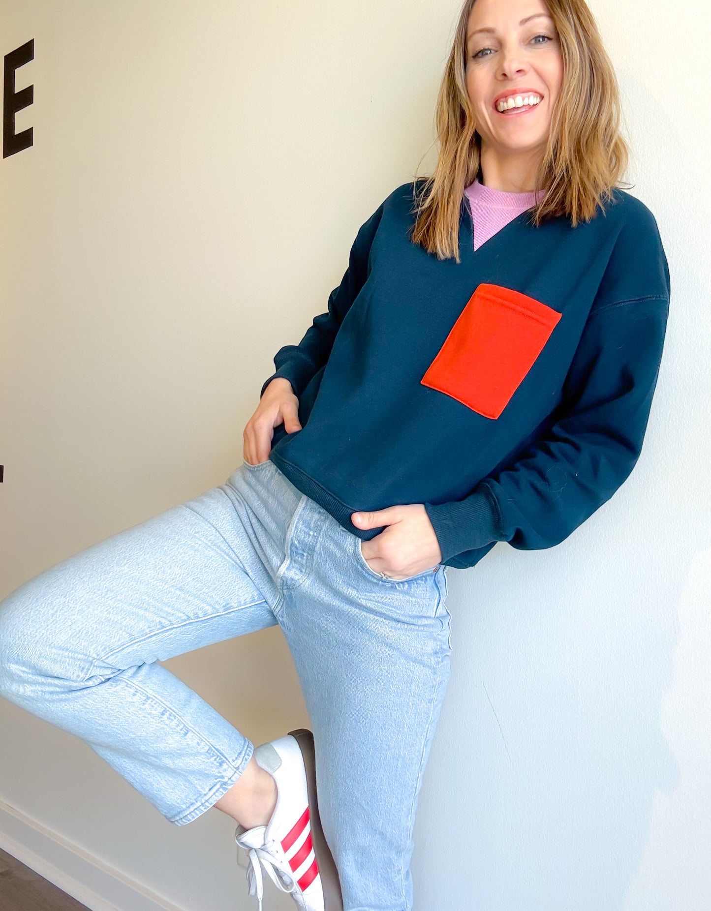 A classic and preppy styled crewneck pullover in dark navy featuring a light purple neckline and contrast orange square pocket on top left chest. Pair with light denim and sneakers for the perfect casual outfit.